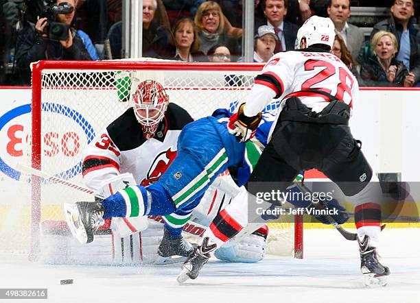 Cory Schneider of the New Jersey Devils keeps an eye on the puck despite activity in front of him during their NHL game against the Vancouver Canucks...