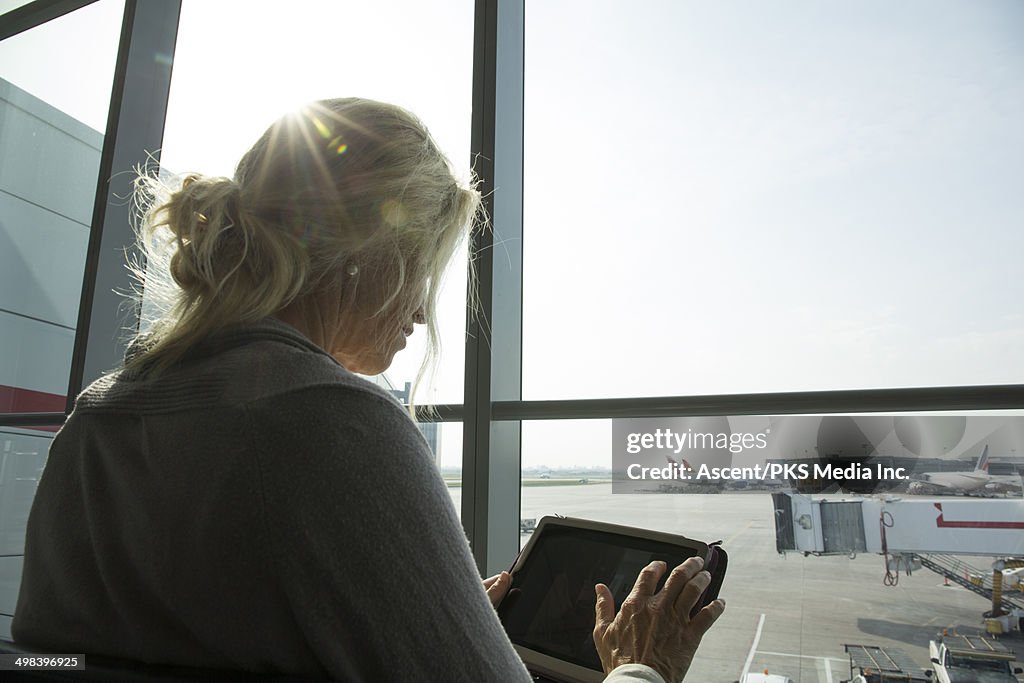 Woman uses digital tablet at airport, sunrise