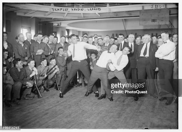 In a publicity photo, boxer Jack Dempsey, magician Harry Houdini, and Benny Leonard stage a mock fight for soldiers, 1920s.