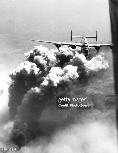 Riding above this towering column of smoke is a Consolidated B-24 Liberator of the 15th AAF after its bombs have started fires in the Astro-Romano...