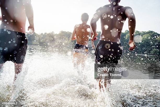 young men running in lake - at the lake stock pictures, royalty-free photos & images