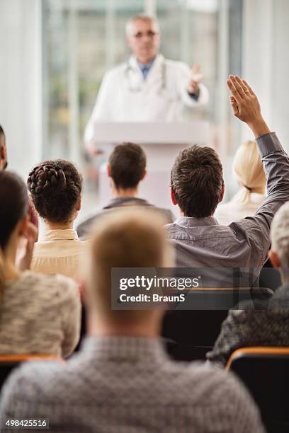 back view of a man asking a question on seminar. - doctor speech stock pictures, royalty-free photos & images