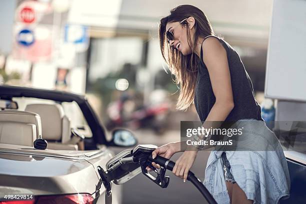 beautiful woman refueling the gas tank at fuel pump. - tank stock pictures, royalty-free photos & images