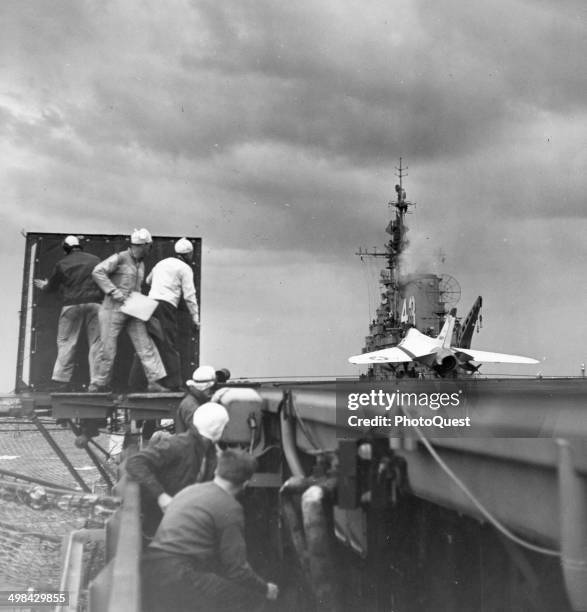 Onboard the USS Coral Sea, a pane taxis forward on the flight deck, October 1953. LSO in background.