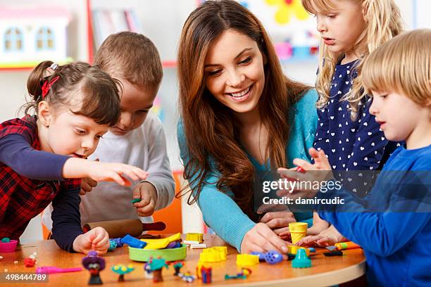 nursery teacher playing with the kids - craft table stock pictures, royalty-free photos & images