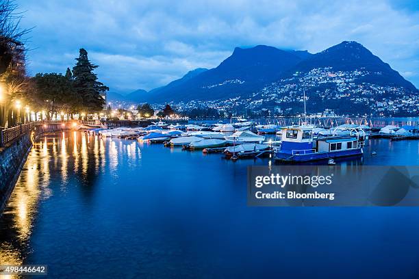 Covered boats sit moored to a jetty on Lake Lugano at dusk in Lugano, Switzerland, on Friday Nov. 20, 2015. The franc is still too strong and the...