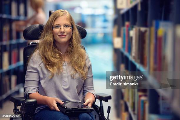 portrait of young woman in wheelchair in library - blonde woman wheelchair stock pictures, royalty-free photos & images