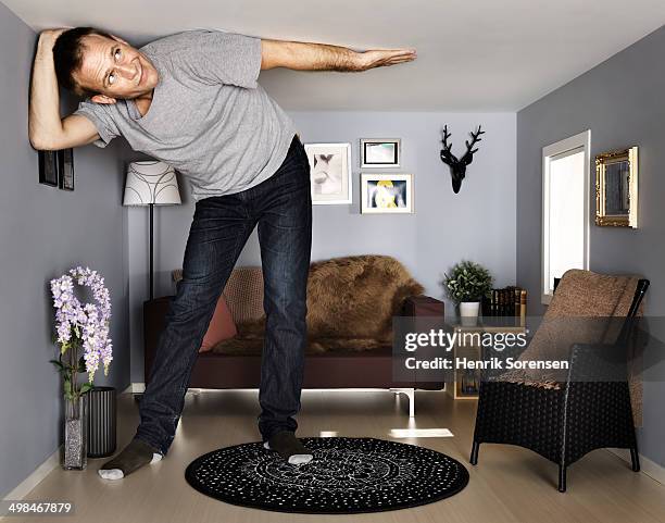 young man in small scale livingroom - claustrophobia stock pictures, royalty-free photos & images