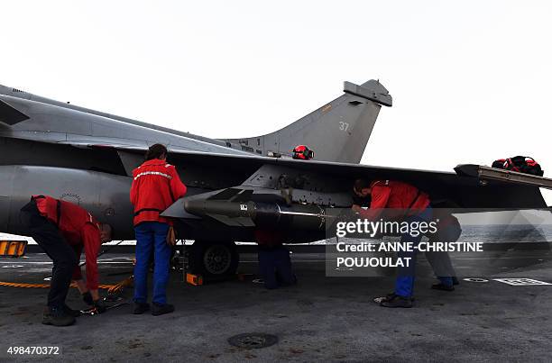 French navy engineers install a missile on a French Rafale fighter aircraft aboard the French Charles-de-Gaulle aircraft carrier, on November 23,...