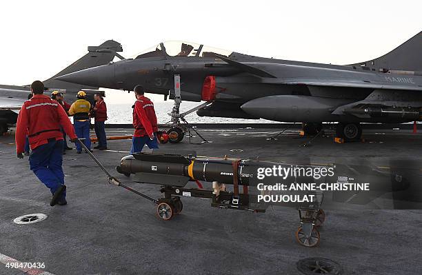French navy engineers install a missile on a French Rafale fighter aircraft aboard the French Charles-de-Gaulle aircraft carrier, on November 23,...