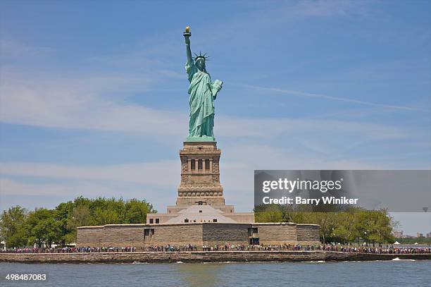 huge line-up of people below base of statue - statue of liberty new york city - fotografias e filmes do acervo