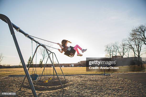 girl swinging high into the sky - kinderspielplatz stock-fotos und bilder