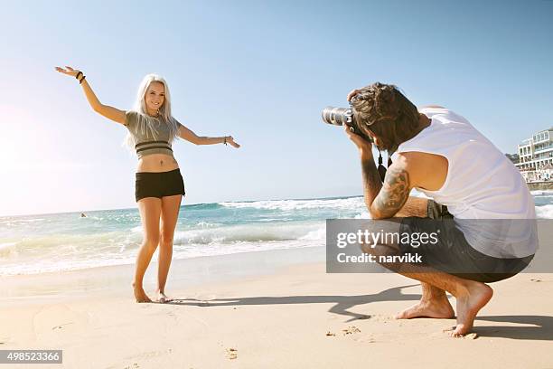 young couple taking photos on the beach - artists model stock pictures, royalty-free photos & images