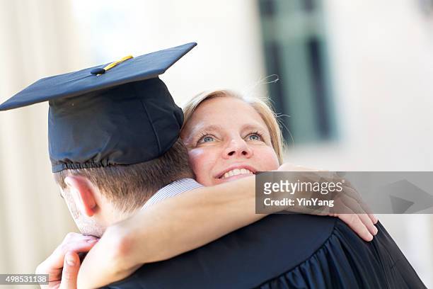 mother embrassing graduating son in graduation ceremony horizontal - son graduation stock pictures, royalty-free photos & images