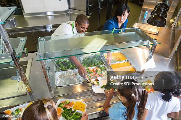 kantinenfrau serviertabletts gesunde speisen für kinder - kantine stock-fotos und bilder