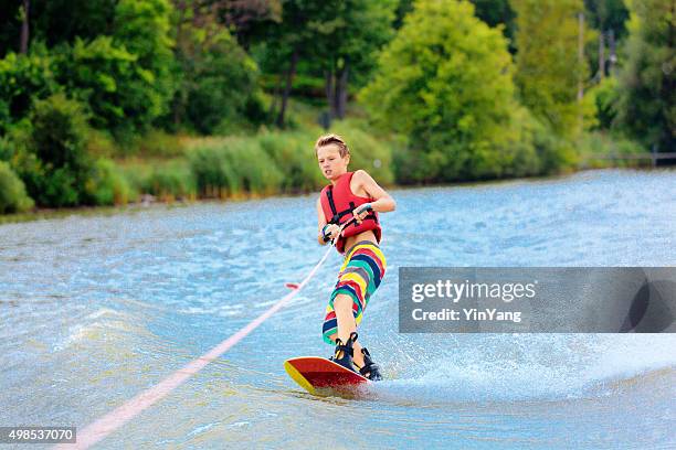 active teen boy water ski boarding on lake in summer - wakeboarding stock pictures, royalty-free photos & images