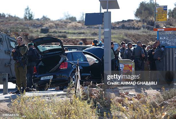 Israeli security forces stand in front of a damaged car at the spot where a Palestinian man was shot by Israeli forces after reportedly ramming a...