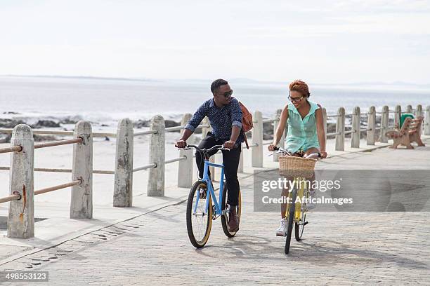 african hipster couple ride along the coast - cape town beach stock pictures, royalty-free photos & images