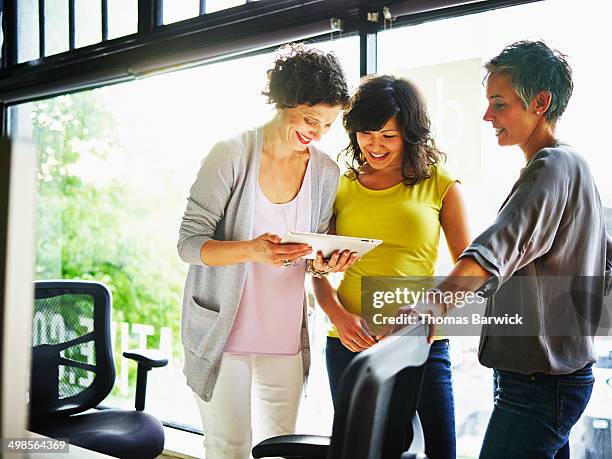three businesswomen working on digital tablet - small office stock pictures, royalty-free photos & images