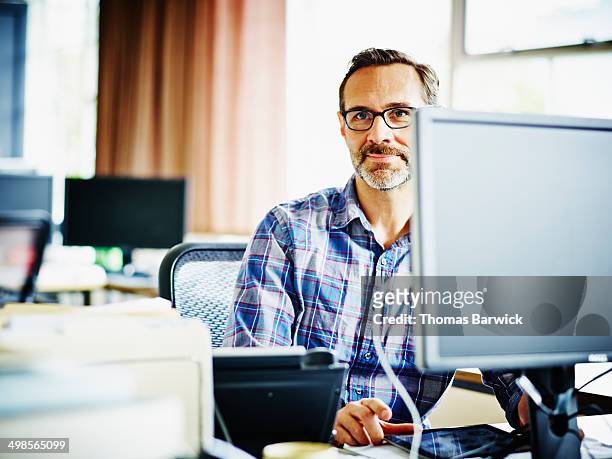 smiling mature businessman sitting at workstation - casual businessman glasses white shirt stock pictures, royalty-free photos & images