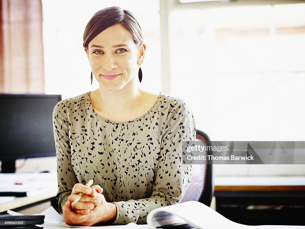 Smiling female businesswoman seated at workstation