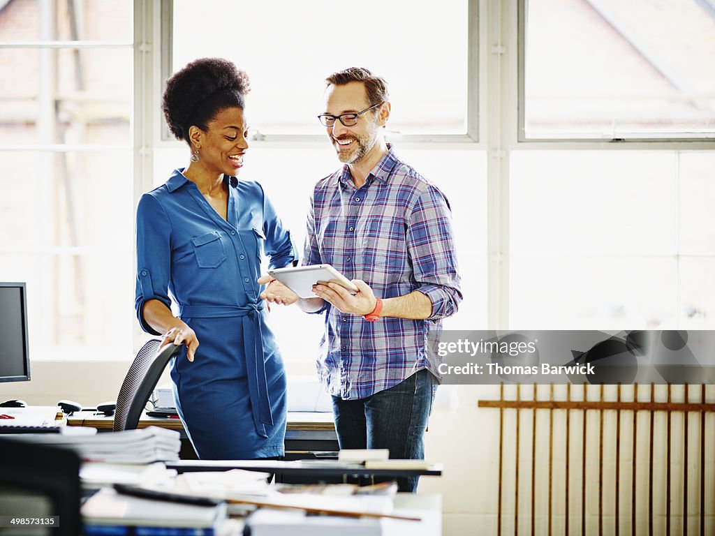 Smiling coworkers discussing project in office
