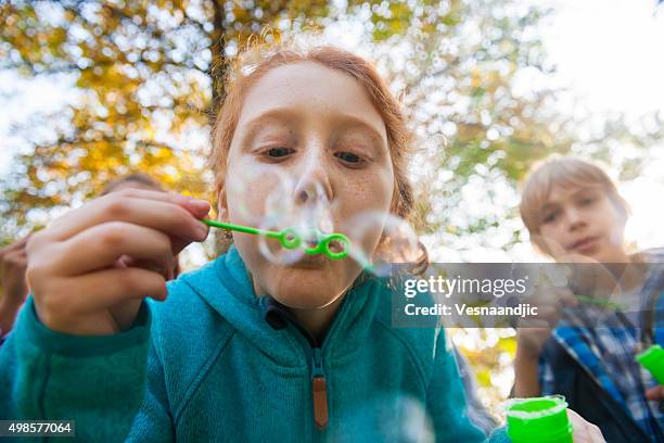 amici blowing bollicine all'aperto - bubble wand foto e immagini stock