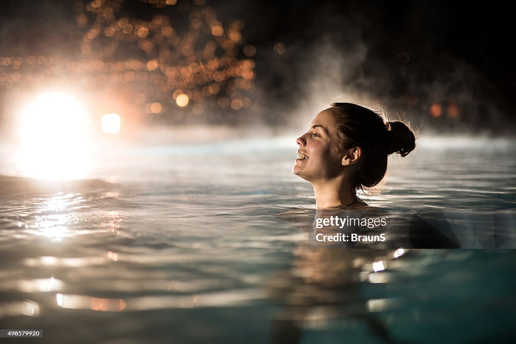 De invierno mujer feliz pasar una noche en la piscina climatizada.