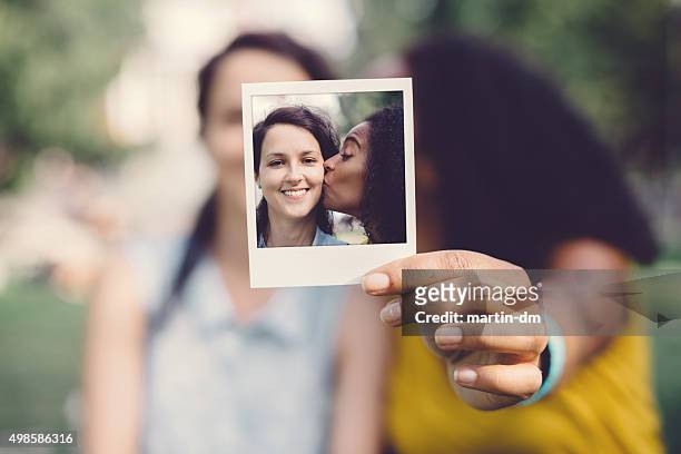instant photo of girl kissing friend on the cheek - cheek kiss stock pictures, royalty-free photos & images