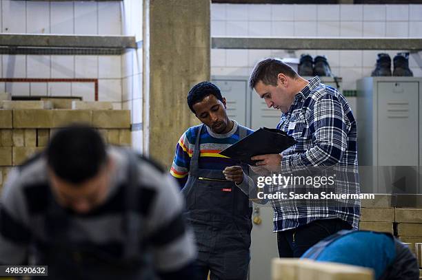 Student with an immigrant background talks to his bricklayer teacher at the Vocational training center of the Chamber of Crafts on November 24, 2015...