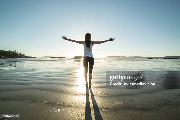 young woman on the beach in autumn arms outstretched - sunrise yoga stock pictures, royalty-free photos & images