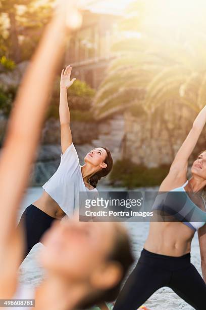 women doing physical yoga exercise outdoors. - physical pressure - fotografias e filmes do acervo