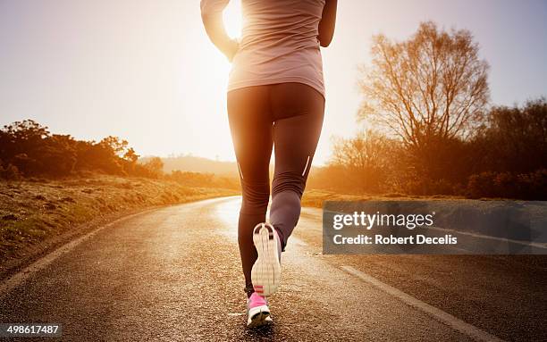 female runner running along road - corrida fora de pista - fotografias e filmes do acervo