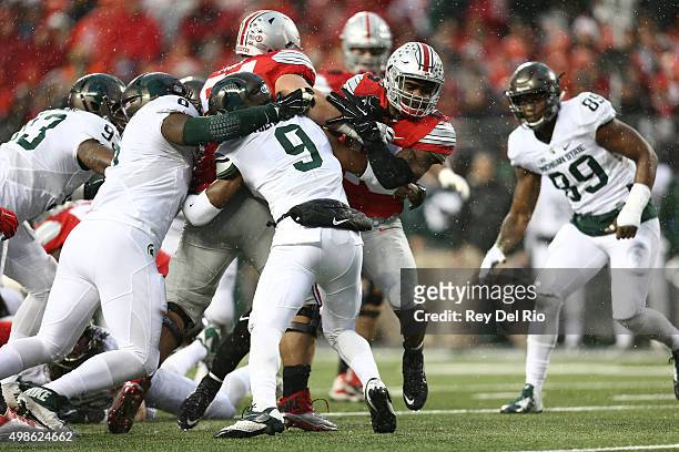 Ezekiel Elliott of the Ohio State Buckeyes carries the ball and tackled by Montae Nicholson of the Michigan State Spartans at Ohio Stadium on...
