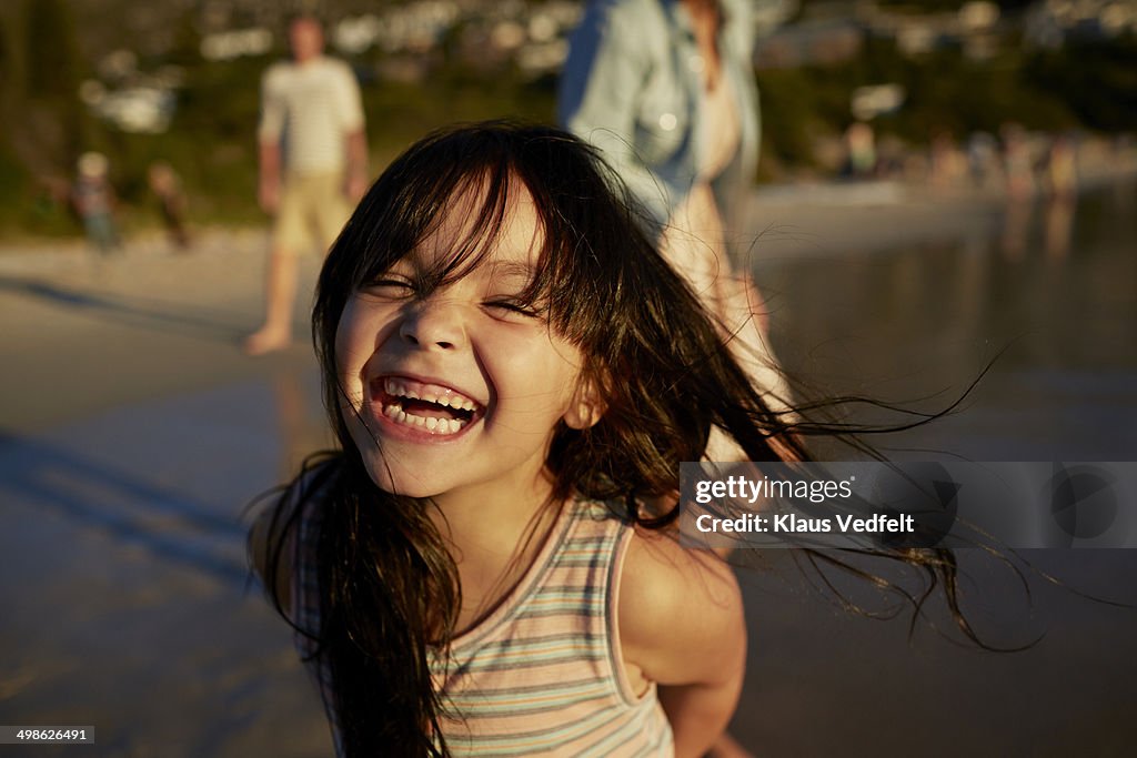 Cute girl standing on beach and laughing