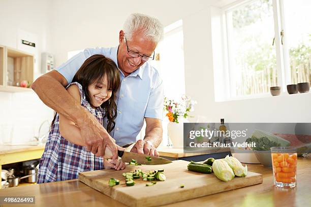 grandfather assisting granddaughter with chopping - kitchen cooking family stockfoto's en -beelden