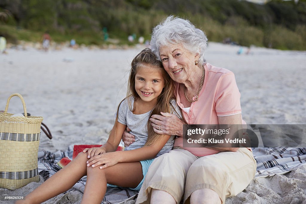 Grandmother & granddaughter sitting on beach