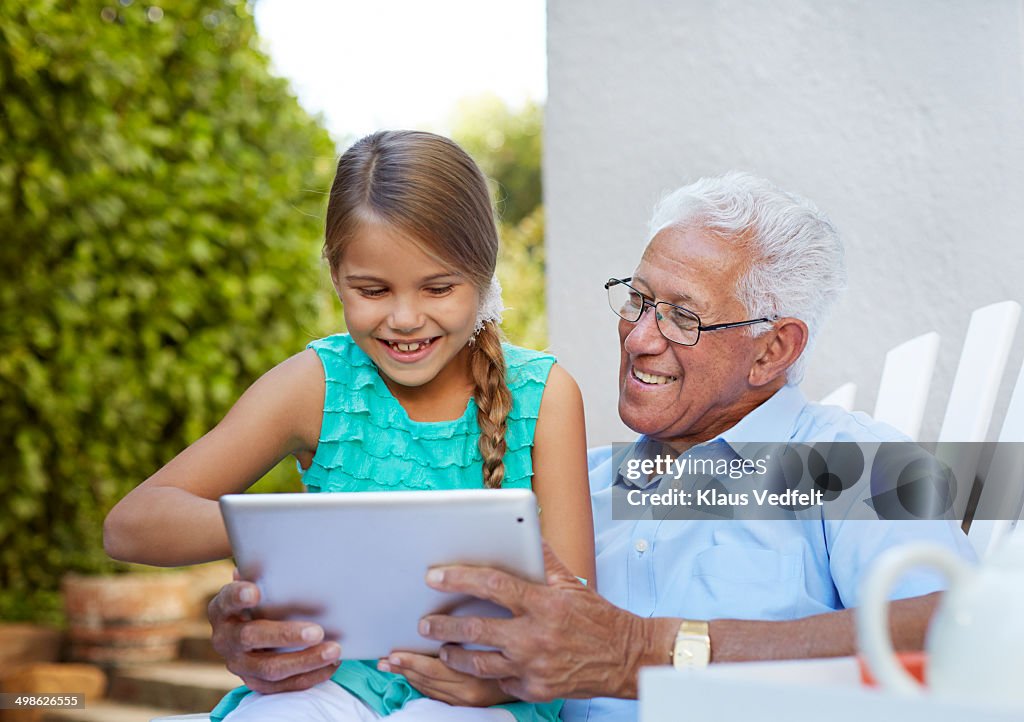 Grandfather & child looking at tablet outside