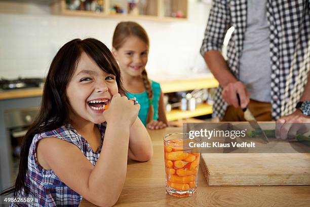 cute girl eating baby carrots in kitchen - babymorot bildbanksfoton och bilder