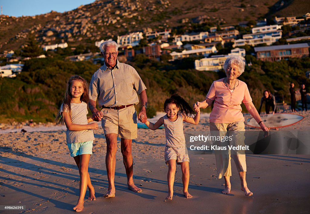 Grandparents & children, holding hands at beach