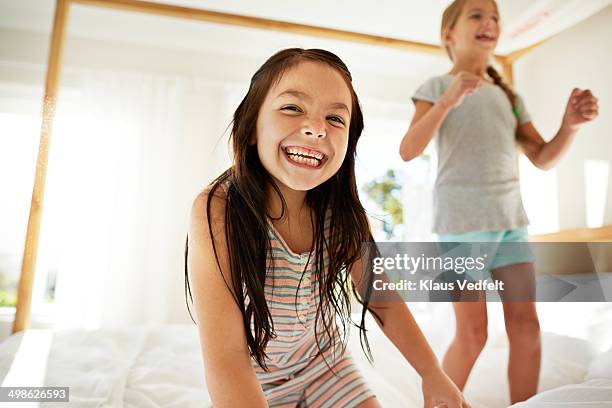 girls jumping in bed & laughing, back light - leanincollection ストックフォトと画像