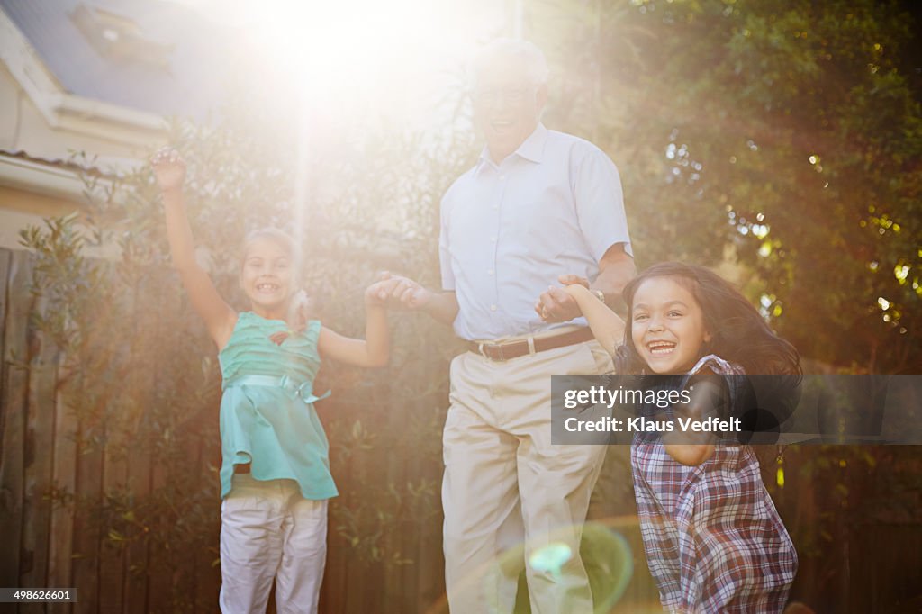 Grandfather jumping with children in garden