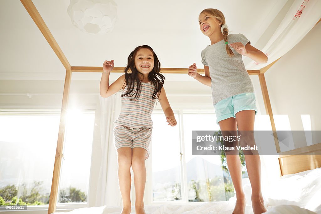 Girls jumping in bed & laughing, back light