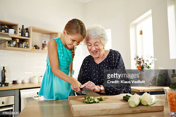 grandmother helping girl with chopping veg - cut in half stock-fotos und bilder