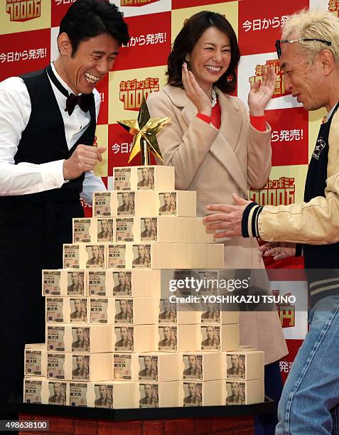 Japanese actor Taizo Harada , actress Ryoko Yonekura and actor Geoge Tokoro smile they display one billion yen in cash, stacked up in the shape of a...