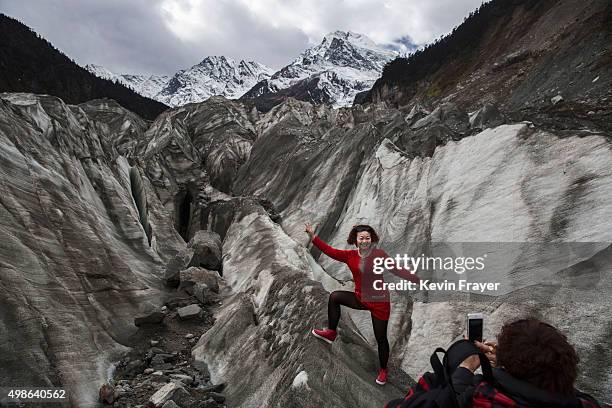 Chinese tourist poses in the tongue of Glacier 1 at the base of the 7,556 m Mount Gongga, known in Tibetan as Minya Konka on November 13, 2015 in...