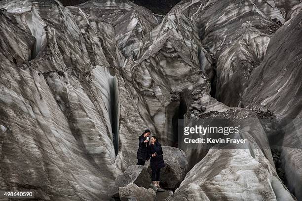 Chinese tourists pose for a picture in the tongue of Glacier 1 at the base of the 7,556 m Mount Gongga, known in Tibetan as Minya Konka on November...