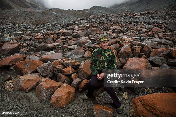 Chinese villager Li Yuanqing who has witnessed the ice slowly receding, sits near the headwaters of the Glacier River and the end of the tongue of...