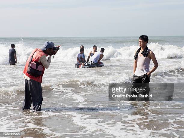 Beach photographer taking photograph of his client in Coxs Bazar sea beach, Bangladesh. Cox's Bazaar is the longest beach in the world. An adorable...