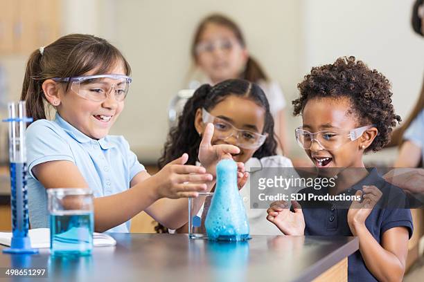 excited girls using chemistry set together in elementary science classroom - school uniform stock pictures, royalty-free photos & images